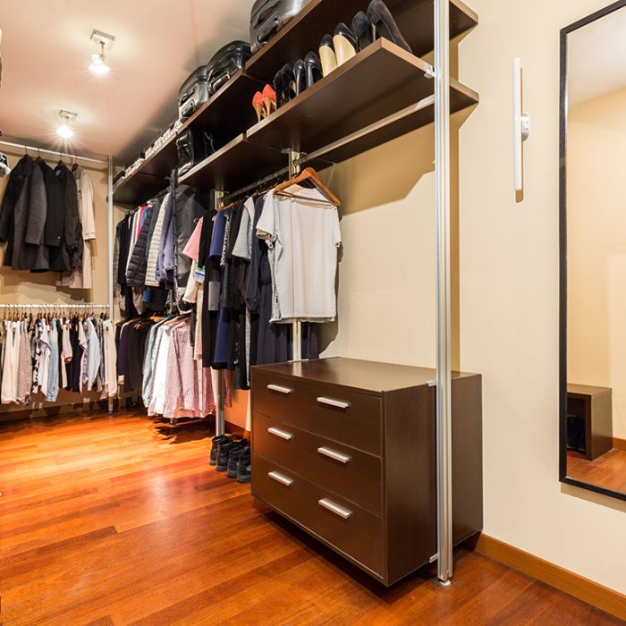Private spacious walk-in closet full of clothes and shoes with wooden wardrobes