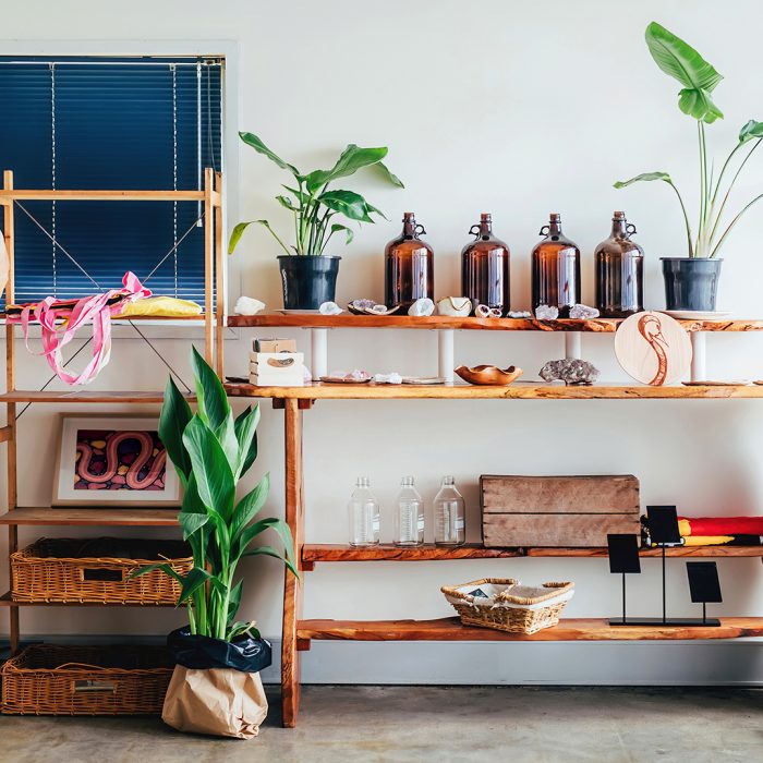 Interior wooden display shelving decorated with old bottles and boxes, crystal stones, pot plants and cane baskets.