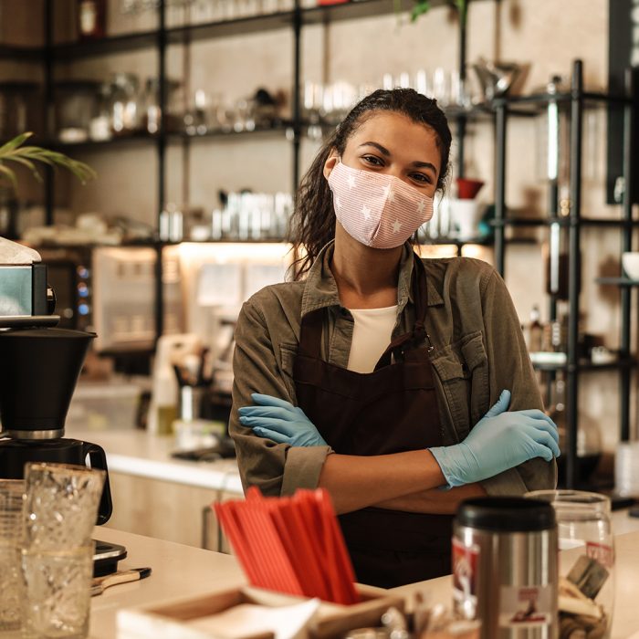 Woman with face mask standing at the counter, shop open after lockdown