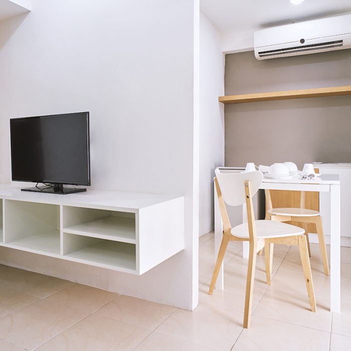 Concept of modern living apartment room decoration with built-in furniture with TV and table set with chairs mock up in the white room